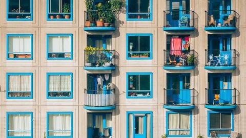 Haus mit vielen Wohnungen und Fenstern Hausansicht mit vielen Wohnungen, türkisen Fenstern und Blumen bepflanzte türkise Balkone