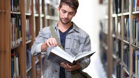 Studium Verwaltung Bild von einem Studenten in einer Bibliothek, der in einem Buch blättert