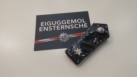 Graduierung 2022 Postkarte der Nachwuchsgewinnung silberne Schrift auf blauem Grund "EIGUGGEMOL ENSTERNCHE", rot-weißes Flatterband mit Polizeistern, eine Schulterklappe mit einem silbernen Stern