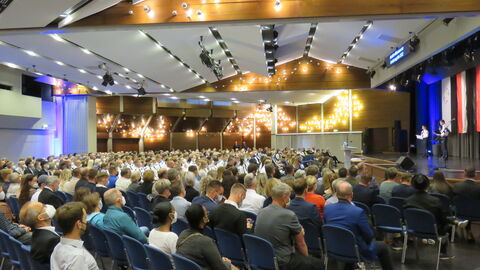 Graduierung 2022 Dezentrale Graduierungsfeier am Campus Kassel in der Stadthalle Baunatal, Blick auf die Bühne, davor Publikum