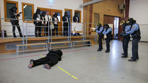 Szenarientraining mit dem DEIG Vorführung und Handhabung des DEIG während des Besuchs der japanischen Delegation an der HöMS, vier Polizeibeamte mit DEIG, eine am boden liegende Person, an der Seite die Zuschauer der Delegation