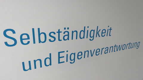 blauer Schriftzug Selbstständigkeit und Eigenverantwortung an der Wand 