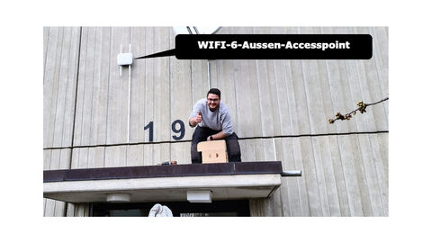 Ein Wifi-6-Aussen-Accesspoint wird an der Wand der Sporthalle in Kassel von einem Techniker montiert