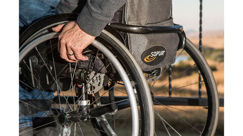 das Bild zeigt einen Menschen im Rollstuhl