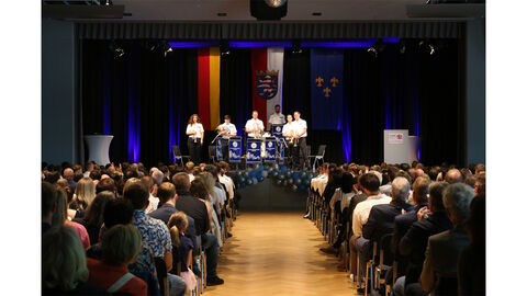 Festsaal Hofheim mit dem Landespolizeiorchester Blick von hinten durchs Publikum auf eine Bühne mit Absolventinnen und Absolventen