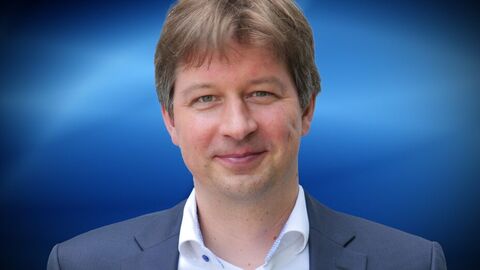 Prof. Dr. Julian Junk Prof. Dr. Julian Junk vor einem blauen Hintergrund