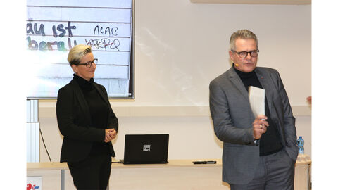 Moderatoren-Team Kathrin Hartmann und Peter Schmidt Im Vordergrund stehen zwei Personen/Moderatoren der Veranstaltung. Kathrin Hartmann links und Peter Schmidt rechts, im Hintergrund der Schriftzug "Hanau ist überall"