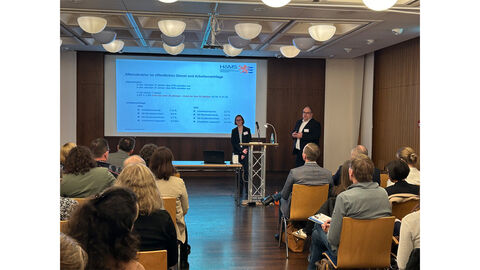 Prof. Dr. Julia Weichel und Prof. Dr. Jochen Hartmannshenn stehen auf einer Bühne vor Publikum