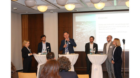 Prof. Dr. Beate Eibelshäuser steht auf einer Bühne mit anderen Diskutierenden beisammen