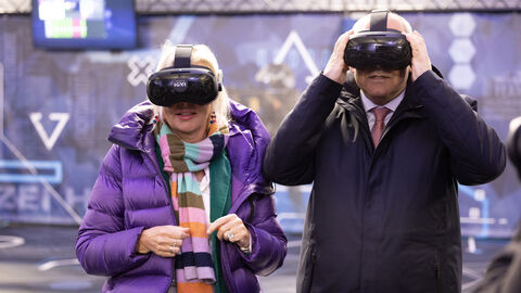 Digitalministerin Sinemus und Innenminister Poseck tragen jeweils eine VR-Brille und blicken damit in die Kamera.