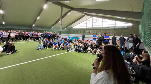 Ansprache von Campusdekanin Sigrid Josephs beim Sporttag des Campus Kasse Sportlerinnen und Sportler sitzen in einem Zelt mit Hallenboden und lauschen der Ansprache von Campusdekanin Sigrid Josephs