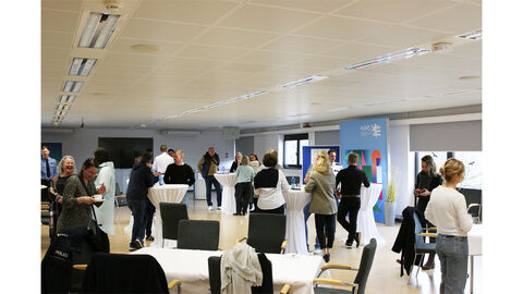 Neue Kolleginnen und Kollegen mit den Beschäftigten der HöMS stehen in einem großen Raum zusammen