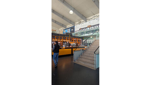 Großmarkthalle Frankfurt Eine große helle Halle; im Vordergrund ein Verkaufsstand ('Frankfurter Kaffeerösterei') mit Regalen, die mit Kaffee gefüllt sind.