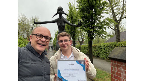 Nach der Verleihung des Industriepreises anlässlich der zehnten Fachtagung Polizeiinformatik im April 2025. Preisträger Marlon Klette (rechts) und Prof. Dr. Steffen Bug (links). Im Hintergrund eine Skulptur. 