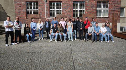 Teilnehmende der Exkursion auf dem Gelände des ehemaligen Stasi-Gefängnis Hohenschönhausen – im Hintergrund eine künstlerische Stahlkonstruktion mit dem Schriftzug „Freiheit“