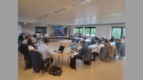 Die neuen Mitglieder des Senats sitzen an Tischen, welche zu einem großen Quadrat zusammengestellt sind.