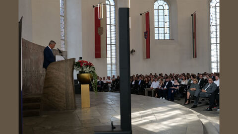 Innenstaatssekretär Martin Rößler steht hinter einem Rednerpult, vor ihm Publikum