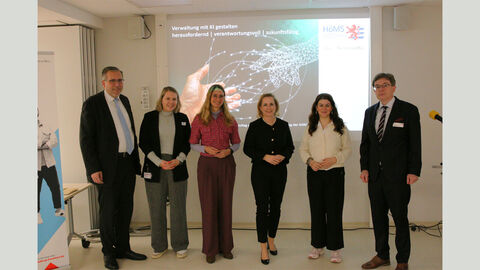 Präsident Dr. Seubert, Dekanin Prof. Dr. Eibelshäuser, Vizepräsident Prof. Dr. Löcher mit Gastreferentinnen des Hochschultages vor einer Leinwand.