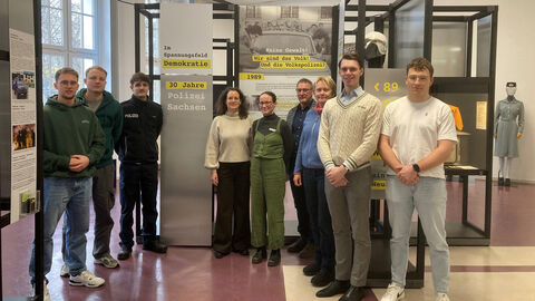 Exkursionsteilnehmende stehen vor den Exponaten des ersten Moduls der Ausstellung „30 Jahre Polizei Sachsen“.