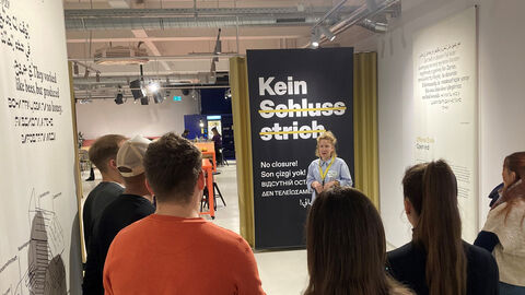 Exkursionsteilnehmende hören der Workshopleiterin Marie-Theres Lewe im Dokumentationszentrums zum NSU-Komplex zu